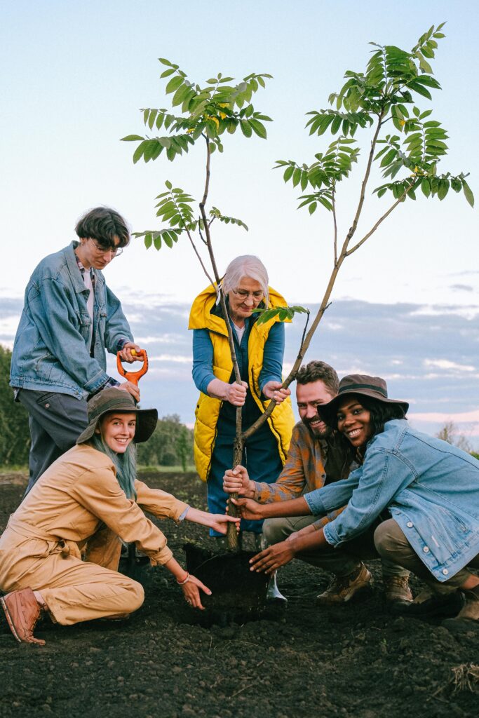 pexels-photo-5029923-5029923 A joyful group of volunteers planting a tree outdoors, symbolizing community and teamwork.